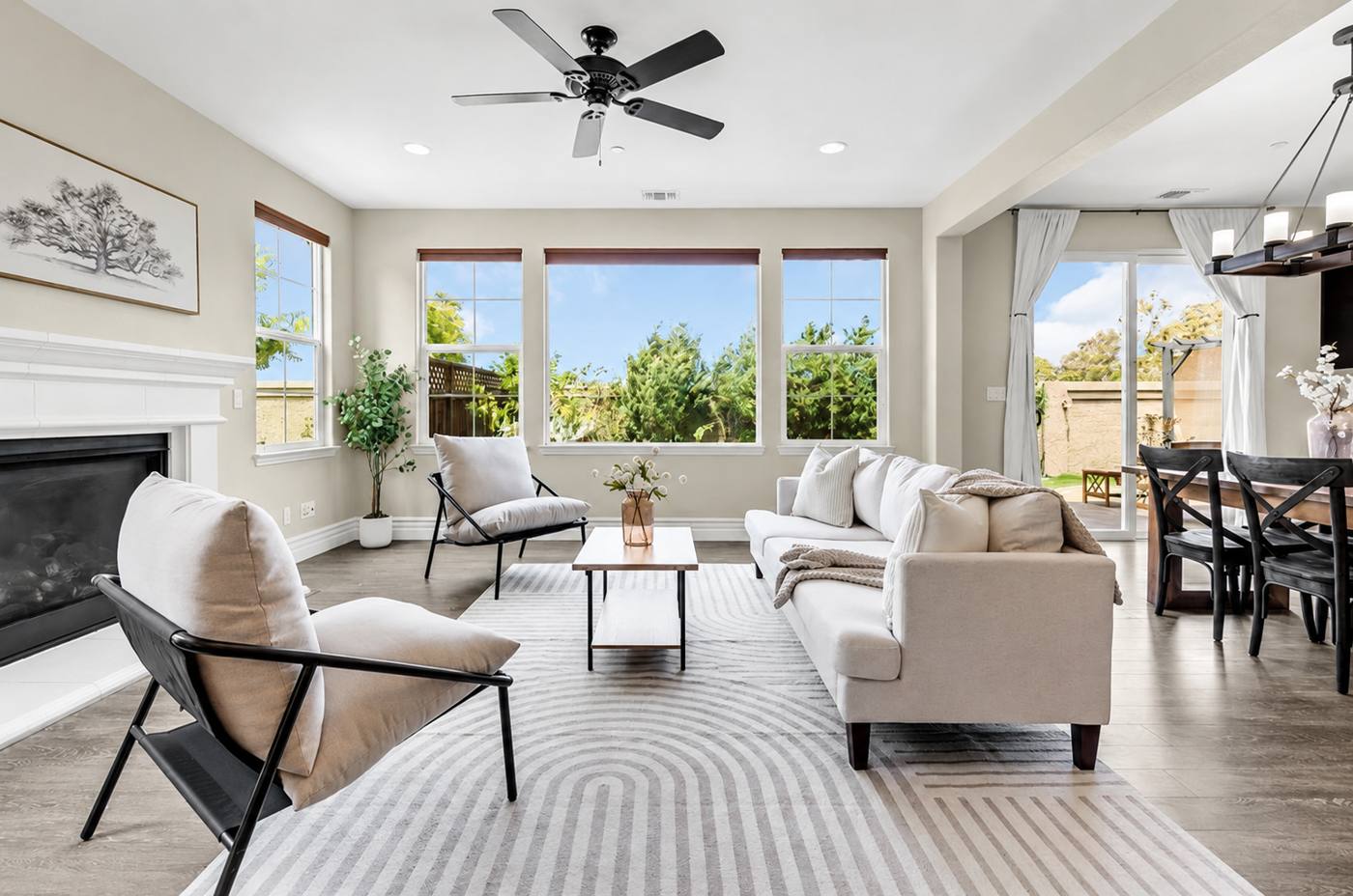 Staged living room with fireplace, sling chairs and a wall of windows onto the garden